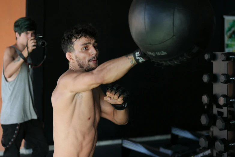 a man standing in front of a punching bag, inspired by Nathan Oliveira, hurufiyya, holding a ball, of a shirtless, profile image