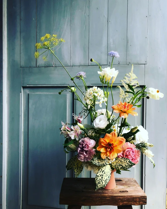 a vase of flowers sitting on top of a wooden table, featured on instagram, chartreuse and orange and cyan, large tall, from the front, celebration