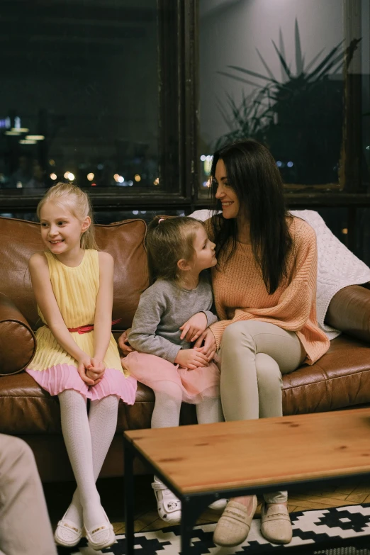 a group of people sitting on top of a brown couch, with a kid, girls, premium quality, trending photo