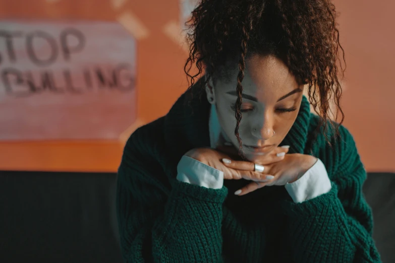 a woman sitting on a couch with her hands on her face, trending on pexels, sitting in the classroom, still image from tv series, curls on top, comforting