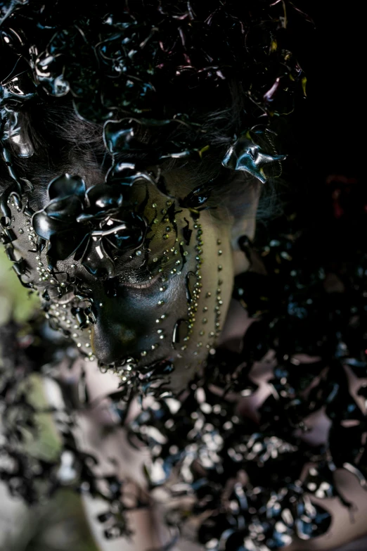 a close up of a woman's face covered in black paint, an album cover, inspired by Alberto Seveso, made of ferrofluid, black pearls, movie filmstill, seaweed and bubles