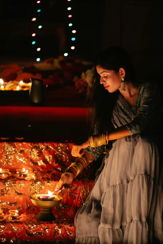 a woman lighting candles in a dark room, pexels contest winner, dressed in a sari, square, holiday, 15081959 21121991 01012000 4k