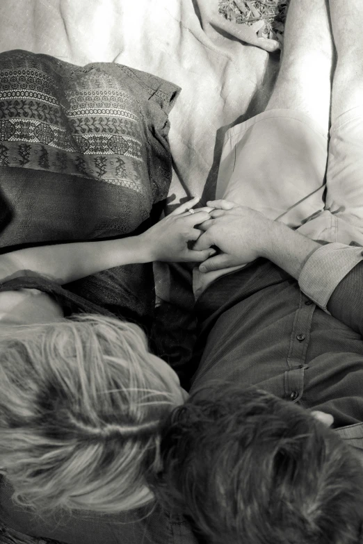 a couple of people laying on top of a bed, a black and white photo, unsplash, romanticism, sitting with wrists together, taken in the mid 2000s, compassion, photograph from above