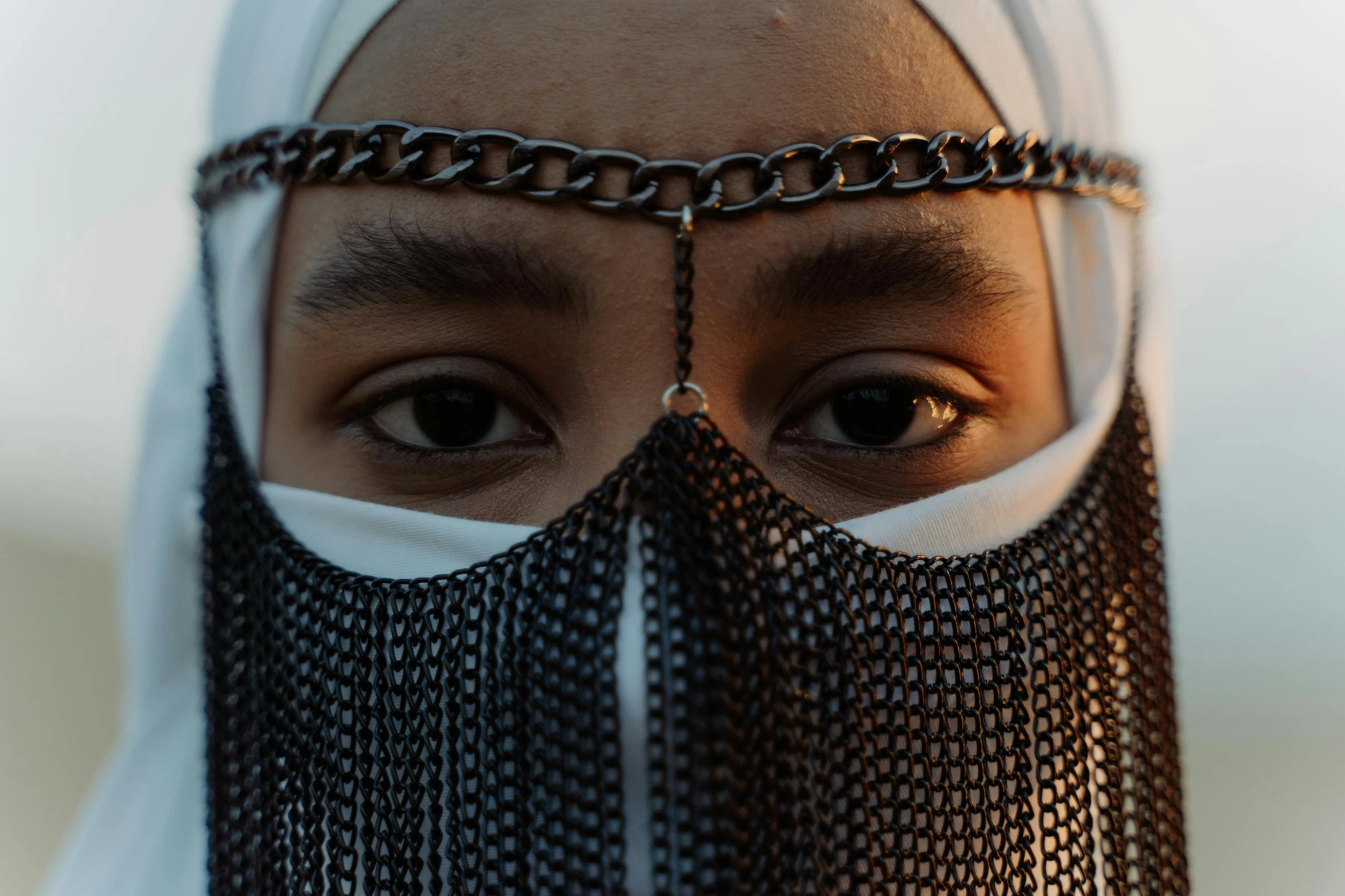 a close up of a person wearing a chain mask, an album cover, trending on pexels, hurufiyya, hijab, eye - level medium shot, front portrait, shot on sony a 7