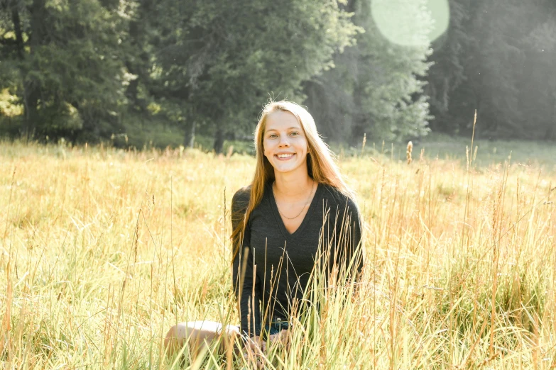 a woman sitting in a field of tall grass, a picture, yearbook photo, brightly lit, forest in the background, avatar image