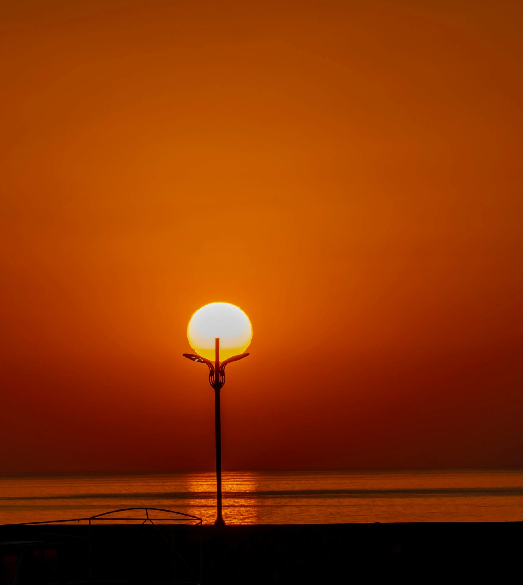 a street light sitting on top of a sandy beach, by Tobias Stimmer, pexels contest winner, big red sun, red sea, orange halo, lamp ( ( ( gym ) ) ) )