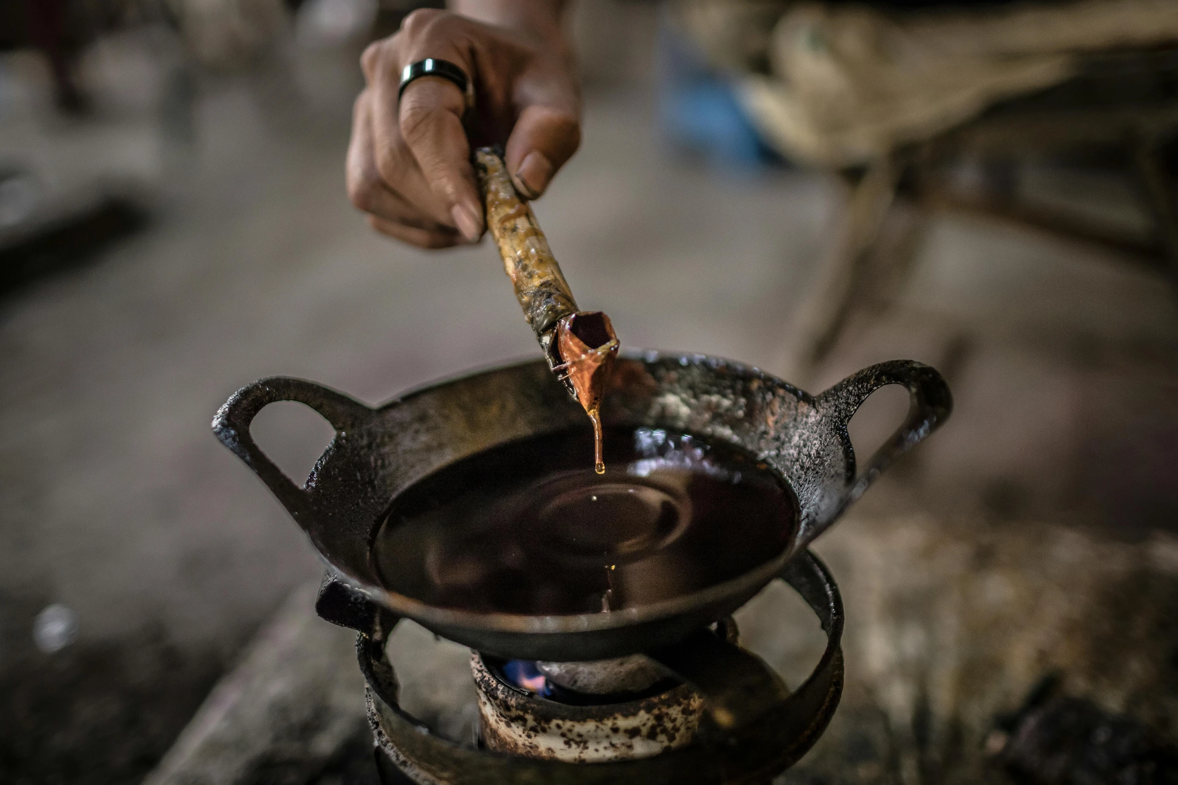 a person pouring something into a pot on top of a stove, inspired by Ceferí Olivé, chocolate. rugged, cambodia, syrup, thumbnail