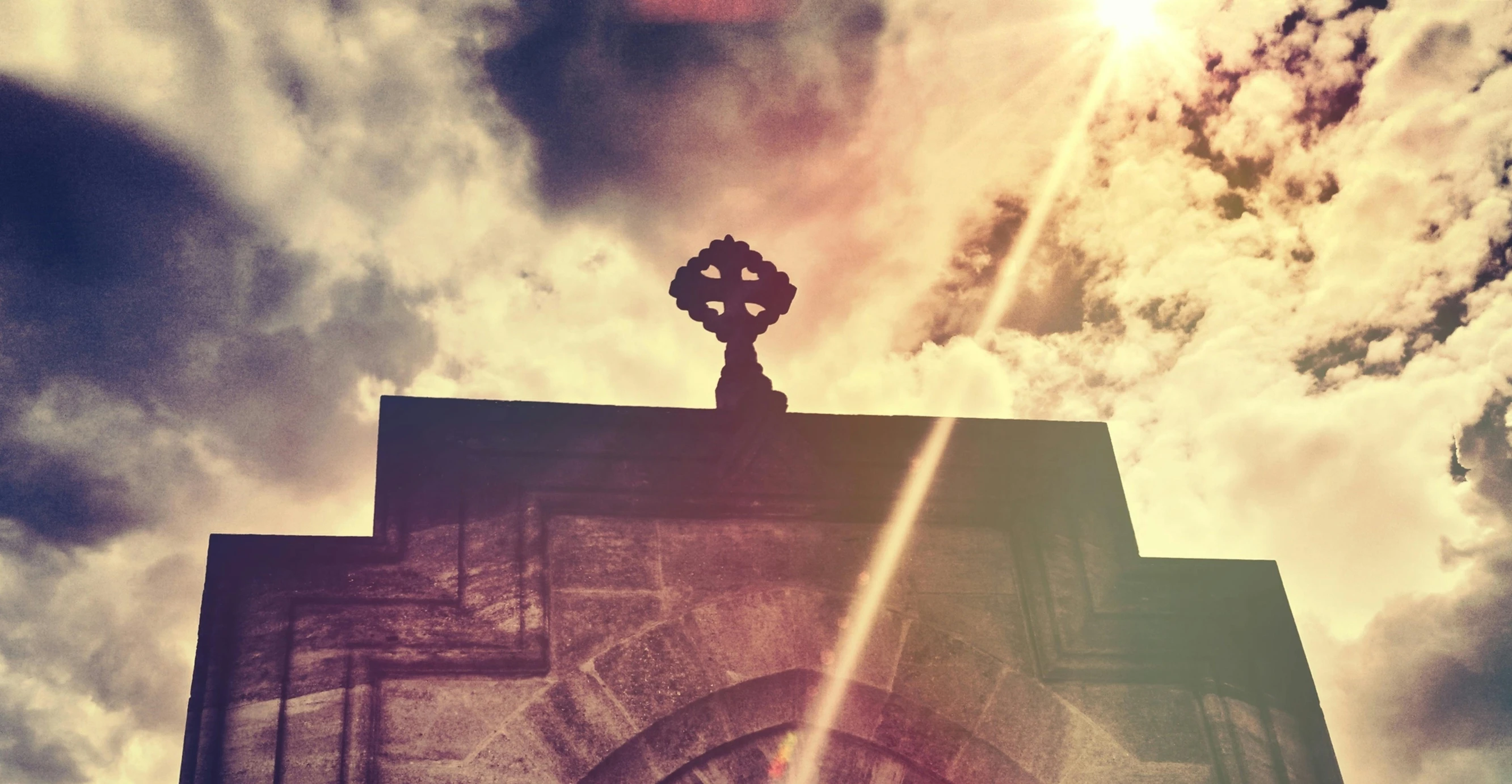 a clock that is on the side of a building, an album cover, unsplash, romanesque, crucifix, sun glare, celtic, looking upwards