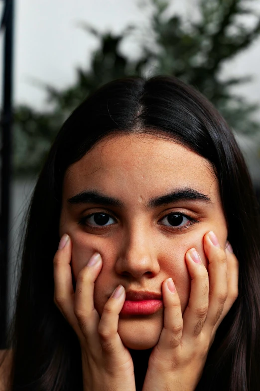 a woman holding her hands to her face, trending on pexels, hyperrealism, heavy eyebrows, portrait of depressed teen, olive skin, girl with black hair