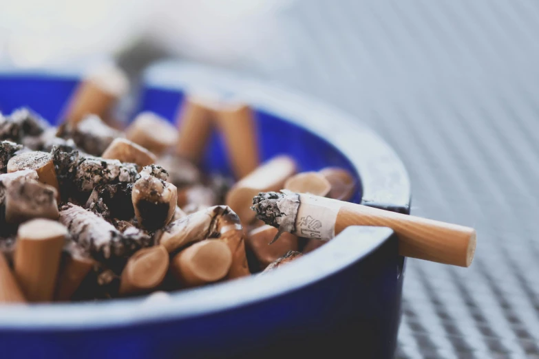 a blue bowl filled with cigarettes on top of a table