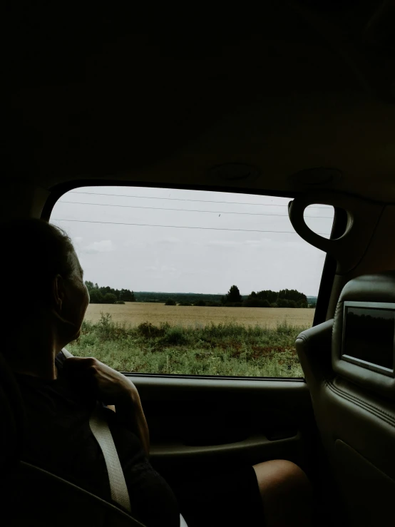 a person sitting in a car looking out the window, by Attila Meszlenyi, in the middle of a field, trip to legnica, instagram photo, very very low quality picture