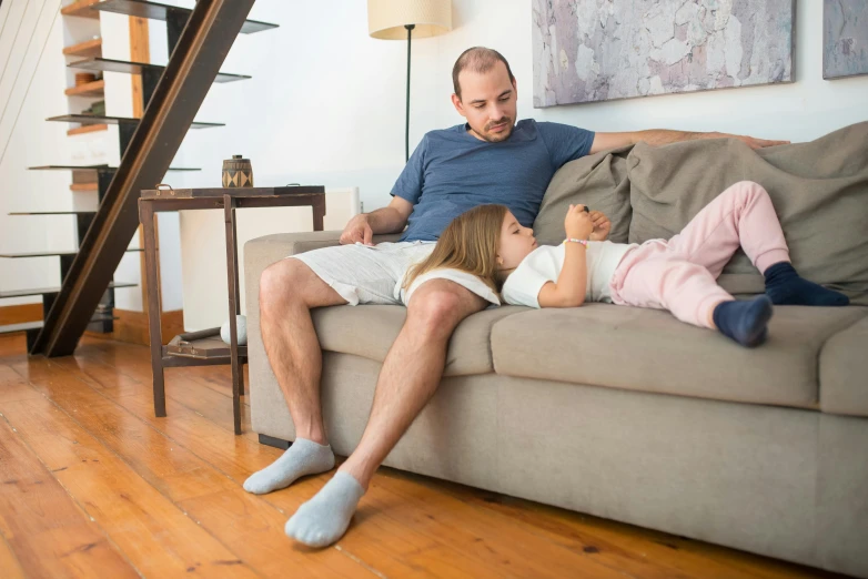 a man and a little girl laying on a couch, pexels, bare leg, calmly conversing 8k, 3 - piece, maintenance