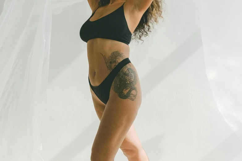 a woman in a black bikini posing for a picture, a tattoo, by Matija Jama, trending on pexels, renaissance, woman is curved, tall and slim, in her early 3 0, profile image