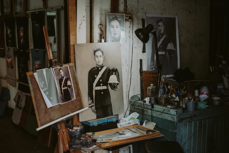 a man that is standing in front of a painting, on a wooden desk