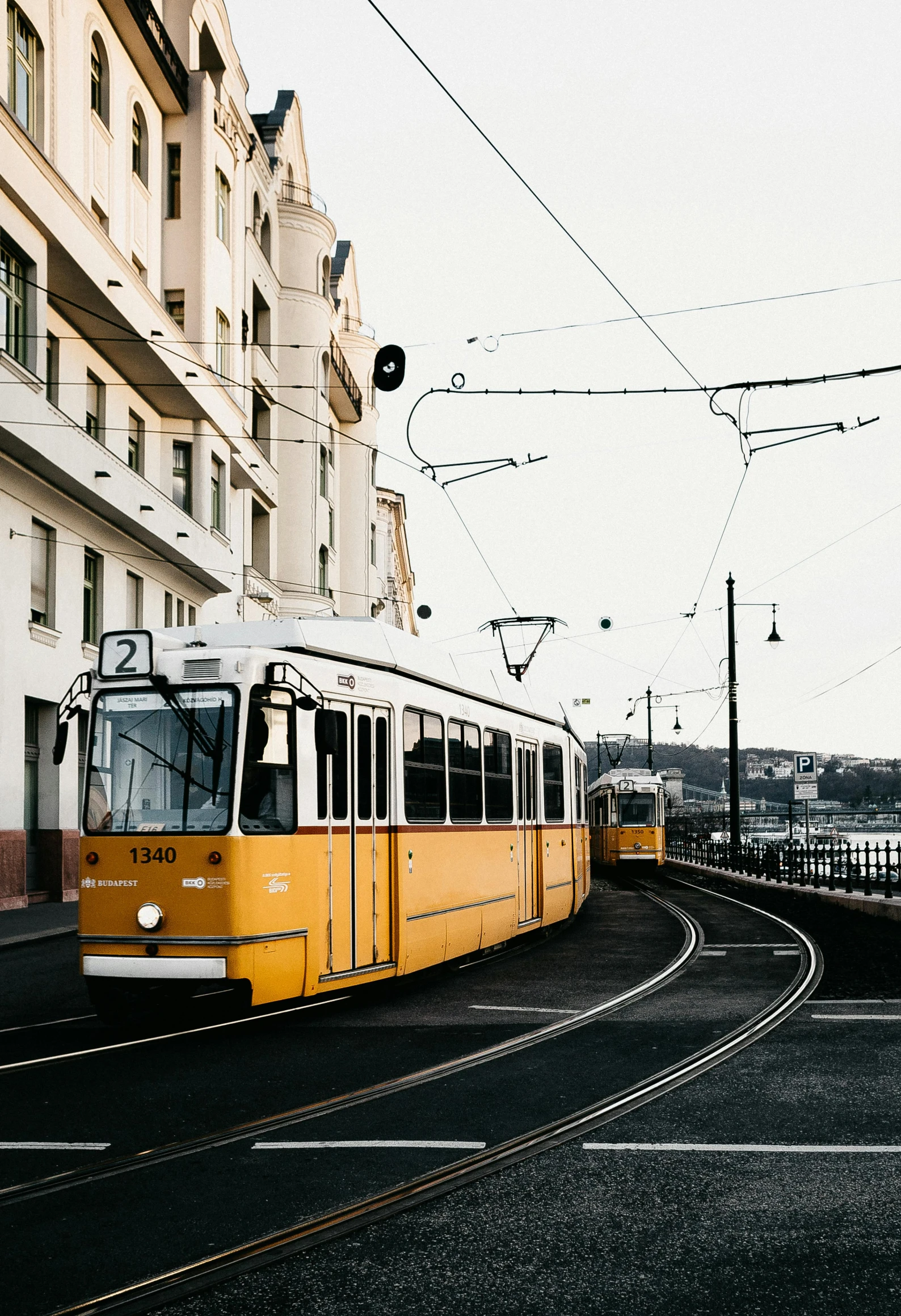 a yellow train traveling down a street next to tall buildings, unsplash contest winner, viennese actionism, trams, seaside, high quality product image”