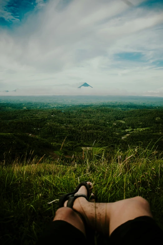 legs resting in grass looking down on a mountain