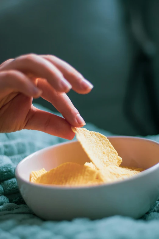 a woman with her hand on a bowl of chips