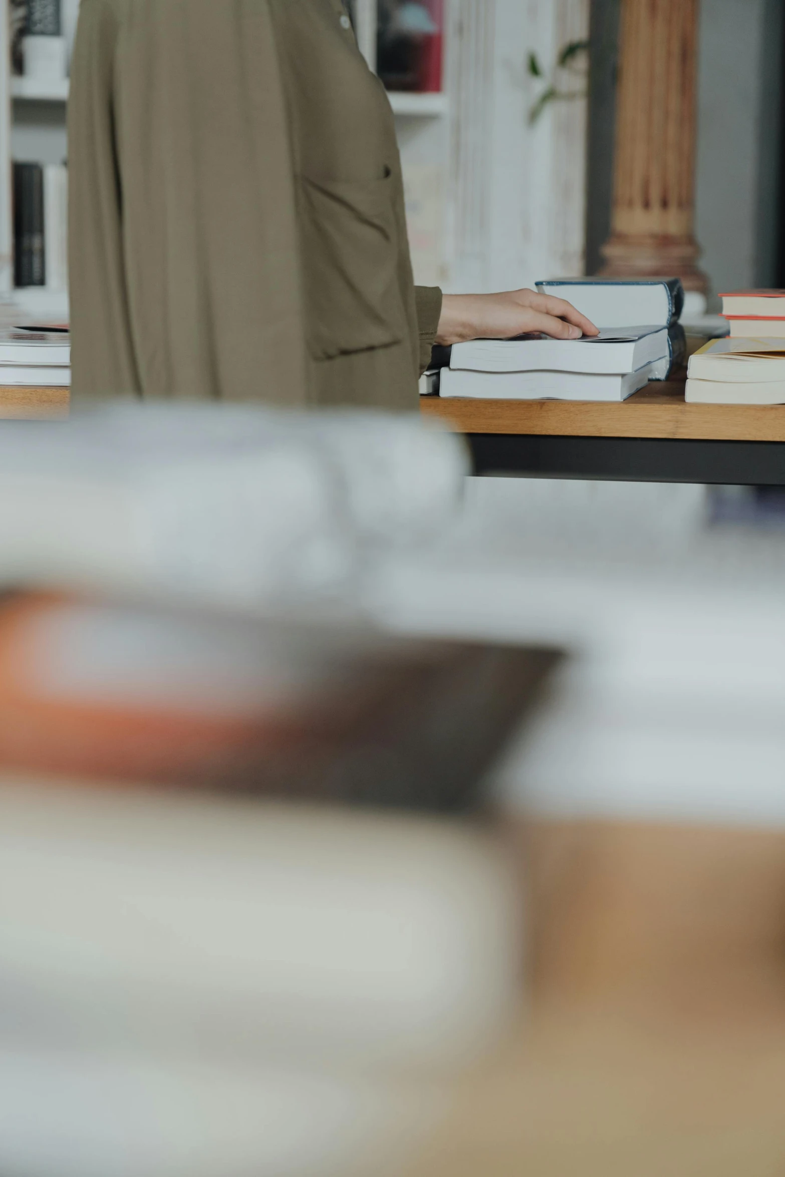 a woman standing in front of a table full of books, by Sebastian Vrancx, trending on unsplash, inspect in inventory image, dynamic closeup, low quality footage, large)}]