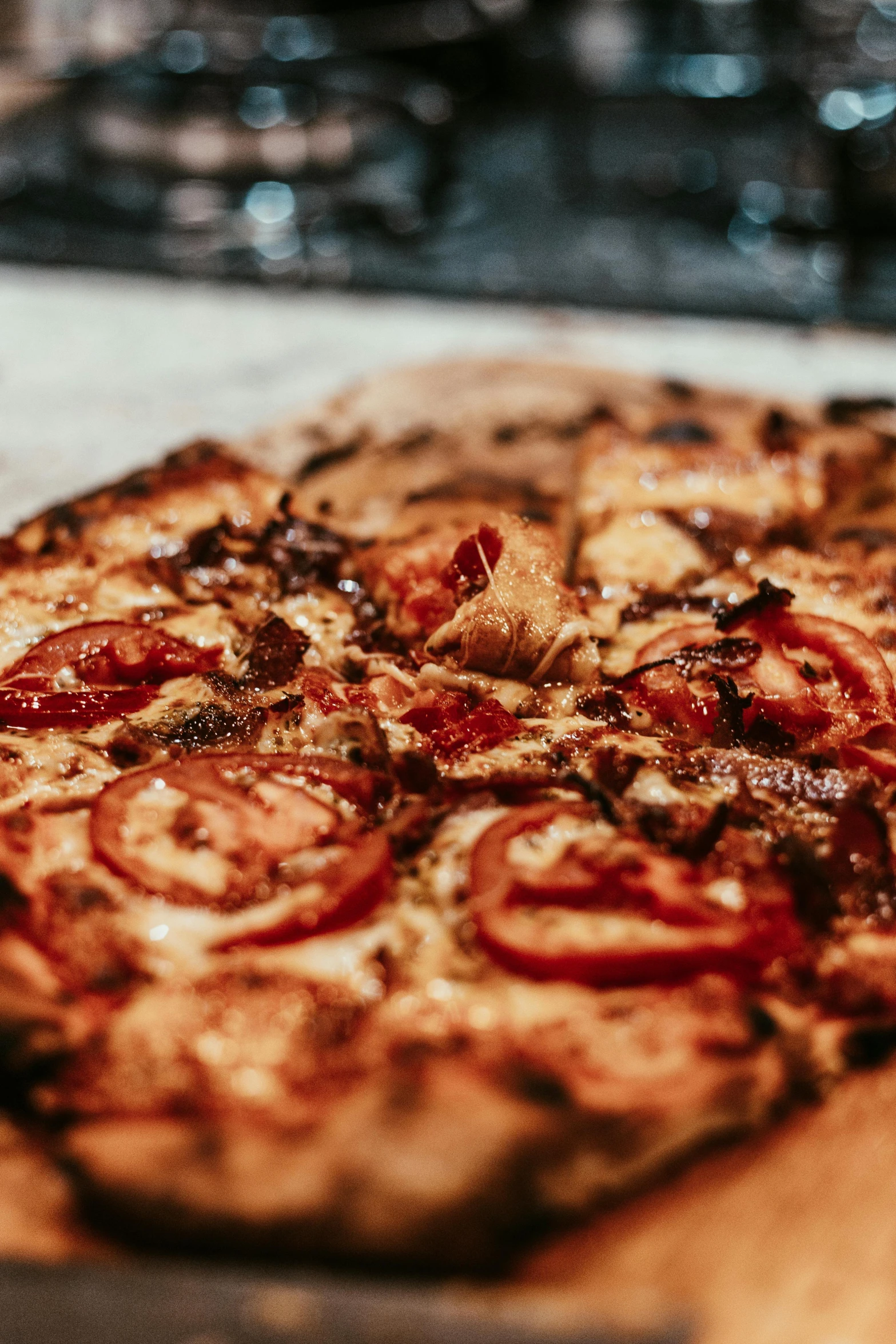 a pizza sitting on top of a wooden cutting board, looking towards the camera, up-close, from the side