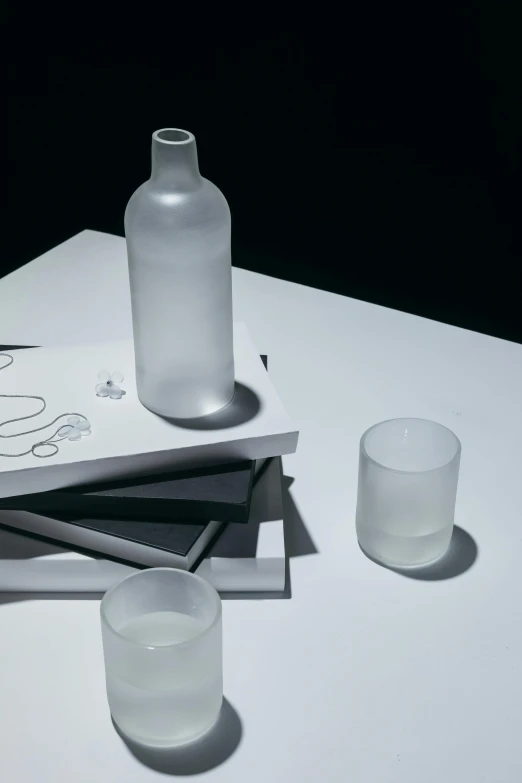 a book sitting on top of a table next to a glass of water, water bottles, style of hiroshi sugimoto, frosted glass, matte material