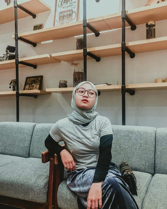 a woman sitting on top of a couch in front of shelves