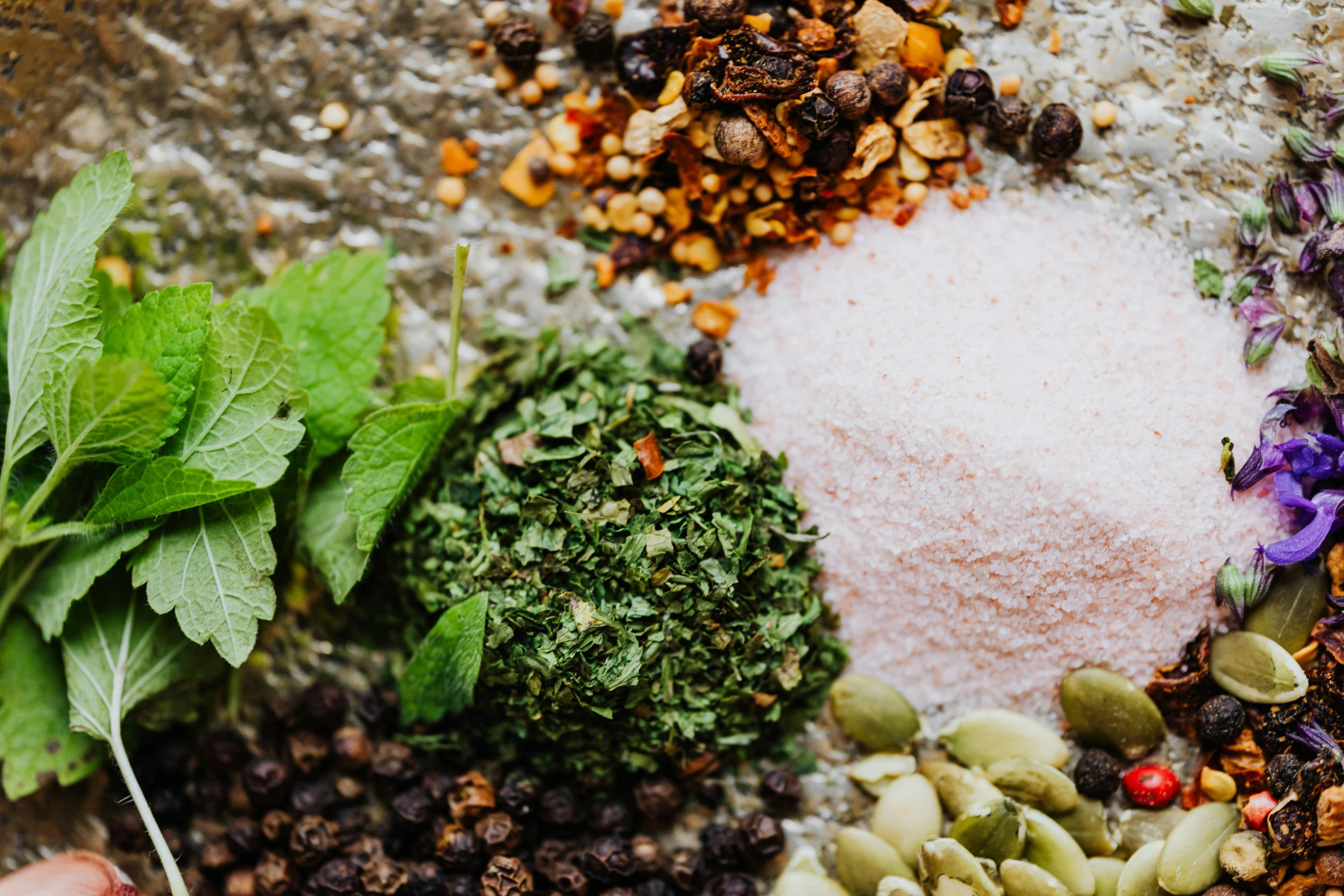 a bowl filled with lots of different types of food, by Julia Pishtar, trending on pexels, renaissance, dried herbs, mint leaves, background image, gravel and scree ground