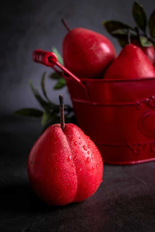 a red bucket filled with red pears on top of a table, a still life, by Arthur Pan, shutterstock contest winner, on black background, red bra, seasonal, drops