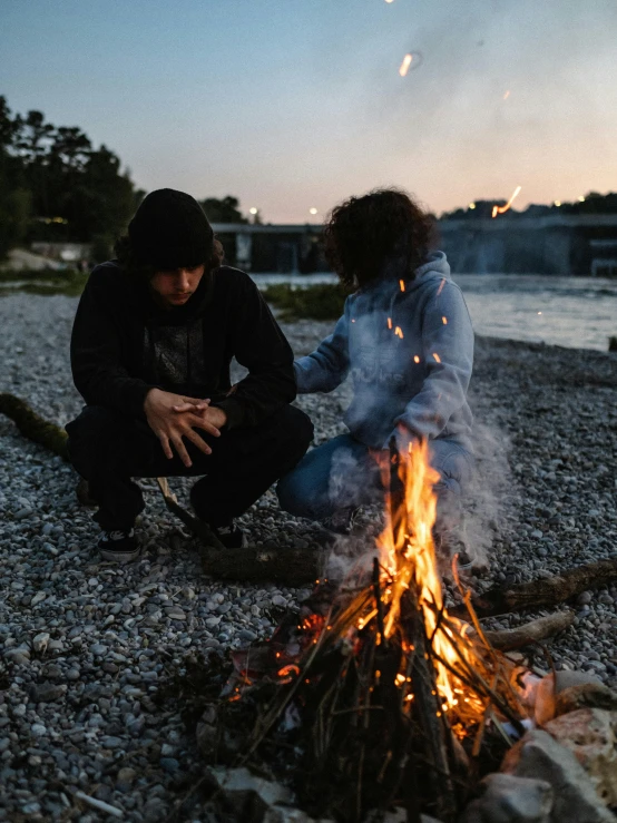 two people setting up a campfire on the beach