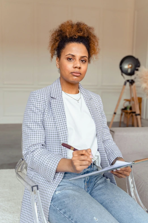 a woman sitting on a couch writing on a clipboard, a portrait, pexels contest winner, mixed race woman, serious business, thumbnail, portrait image