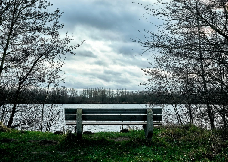 a bench sitting in the grass next to a lake
