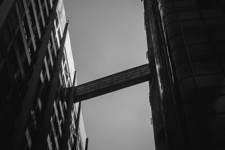 a black and white photo of two tall buildings, a black and white photo, pexels contest winner, steel archways, sky bridges, view from the streets, london architecture