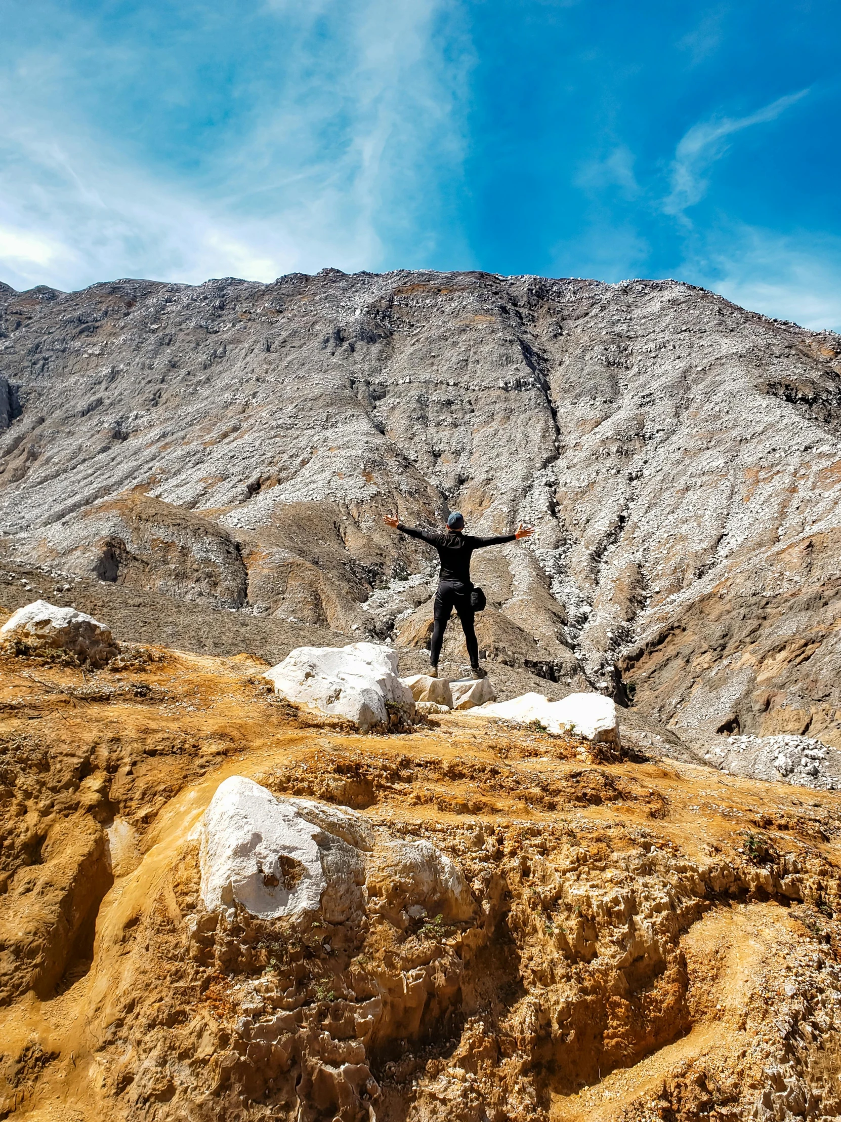 person on the mountain on his knees holding his arms wide