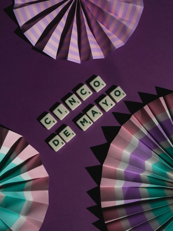 a group of paper fans sitting on top of a purple wall, an album cover, by Carey Morris, pexels contest winner, a rubik's cube, lettering, mexico city, pair of keycards on table