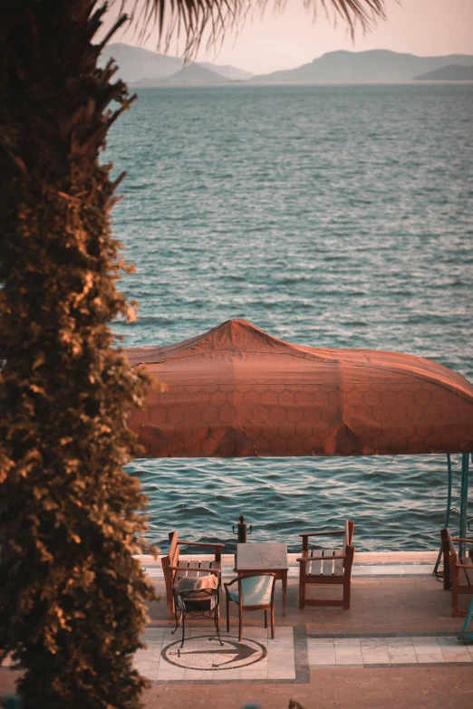 outdoor dining table and umbrella on concrete area near body of water