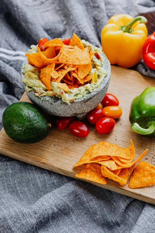 a wooden cutting board topped with chips and vegetables, a still life, trending on pexels, chilaquiles, grey, avocado chair, detailed product image