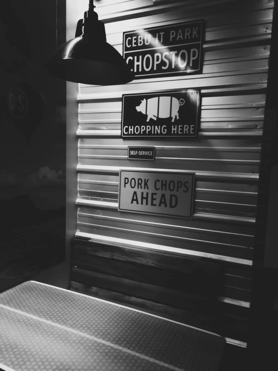 a black and white photo of a table and a lamp, by Ben Thompson, unsplash, happening, in a butcher shop, old signs, pork, snapchat photo