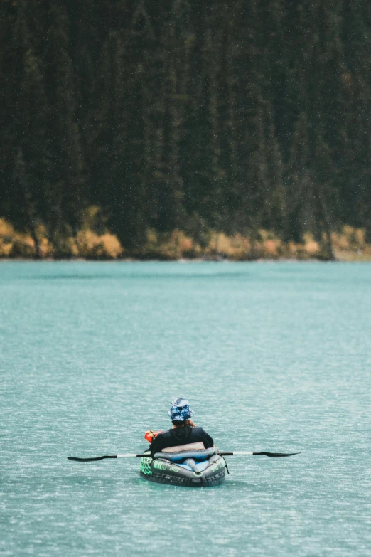 a man in a kayak paddling across a lake, pexels contest winner, banff national park, inflatable, paul barson, on the bow