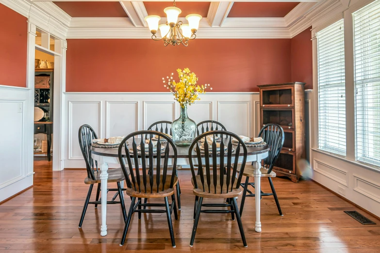 the table has chairs around it and an arrangement of flowers in a vase