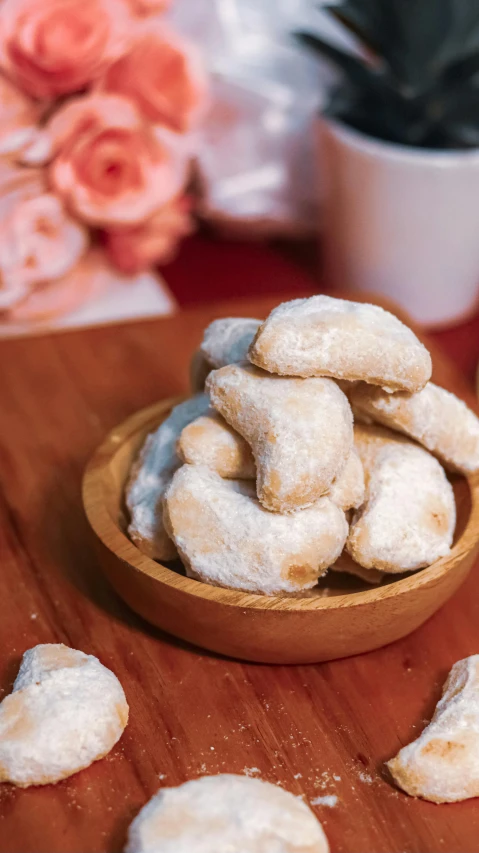 a bowl of cookies sitting on top of a wooden table, kuntilanak, medium-shot, very romantic, donut