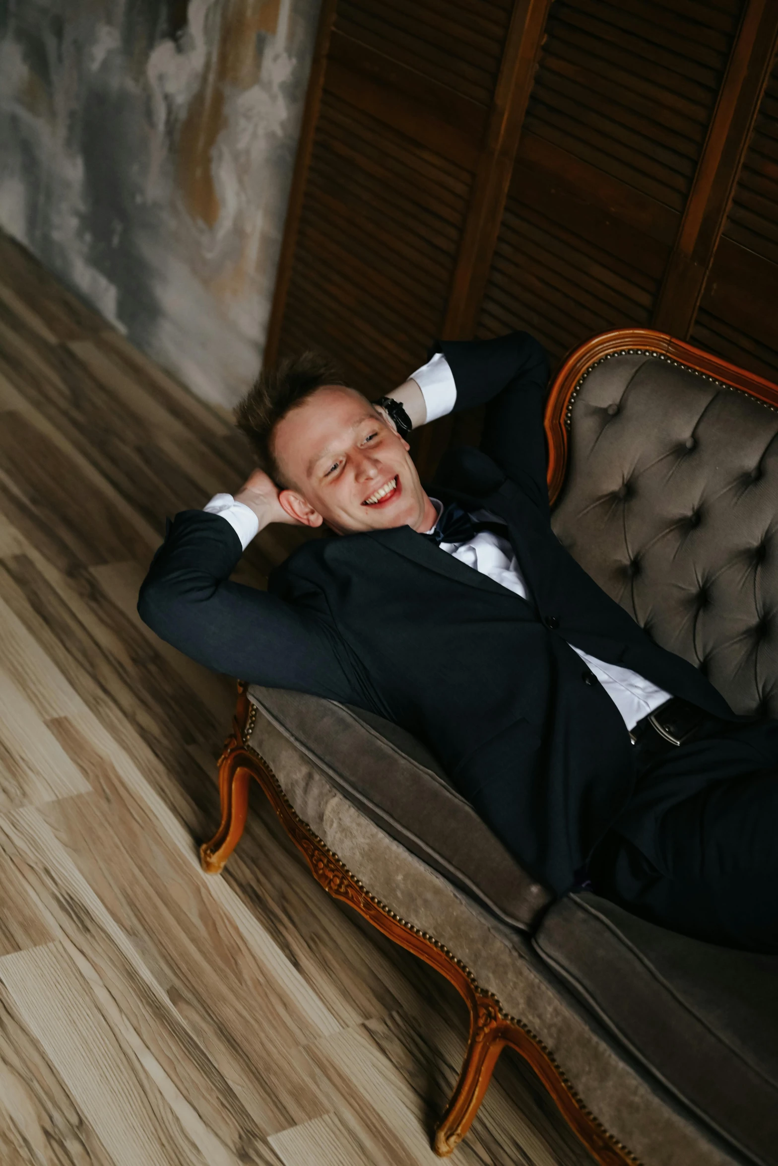 a man in a tuxedo laying on a couch, inspired by Dmitry Levitzky, pexels contest winner, baroque, smiling down from above, wearing causal black suits, wedding, satisfied pose