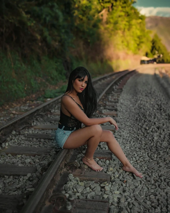 a woman sitting on train tracks, posing for a po