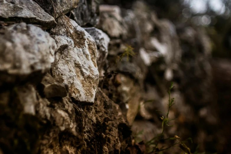 a stone wall with moss growing on it, an album cover, unsplash, background image, cinematic, gravels around, ((rocks))