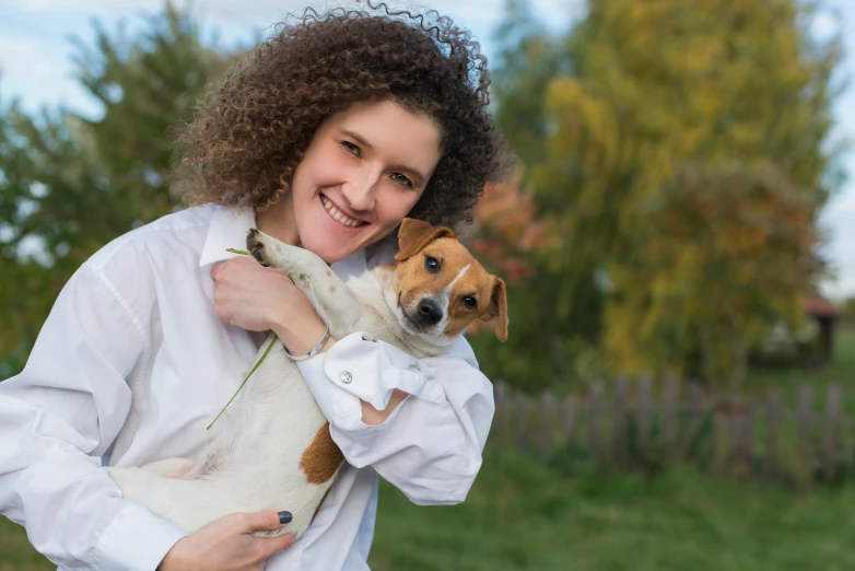 a woman holding a dog in her arms, by Julia Pishtar, pixabay contest winner, wearing lab coat and a blouse, avatar image, alexey gurylev, outdoor photo