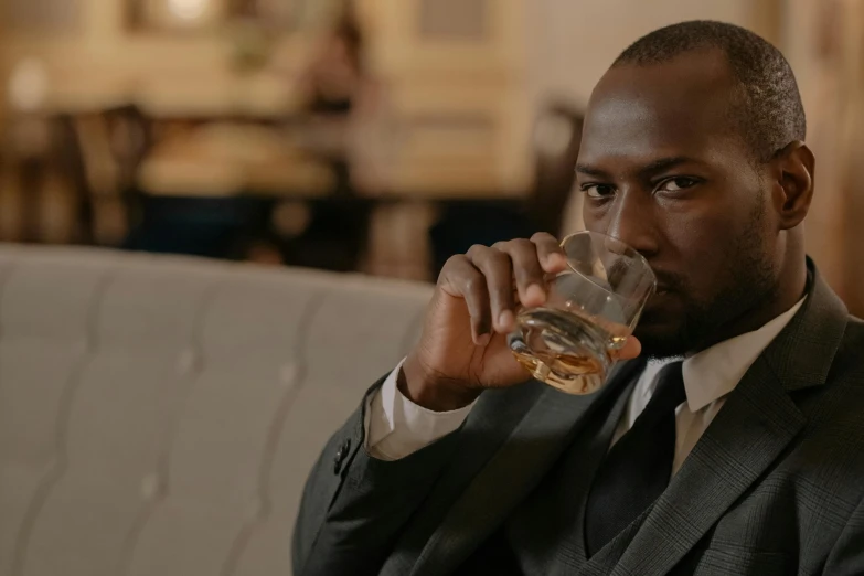 a man in a suit sipping a glass of whisky