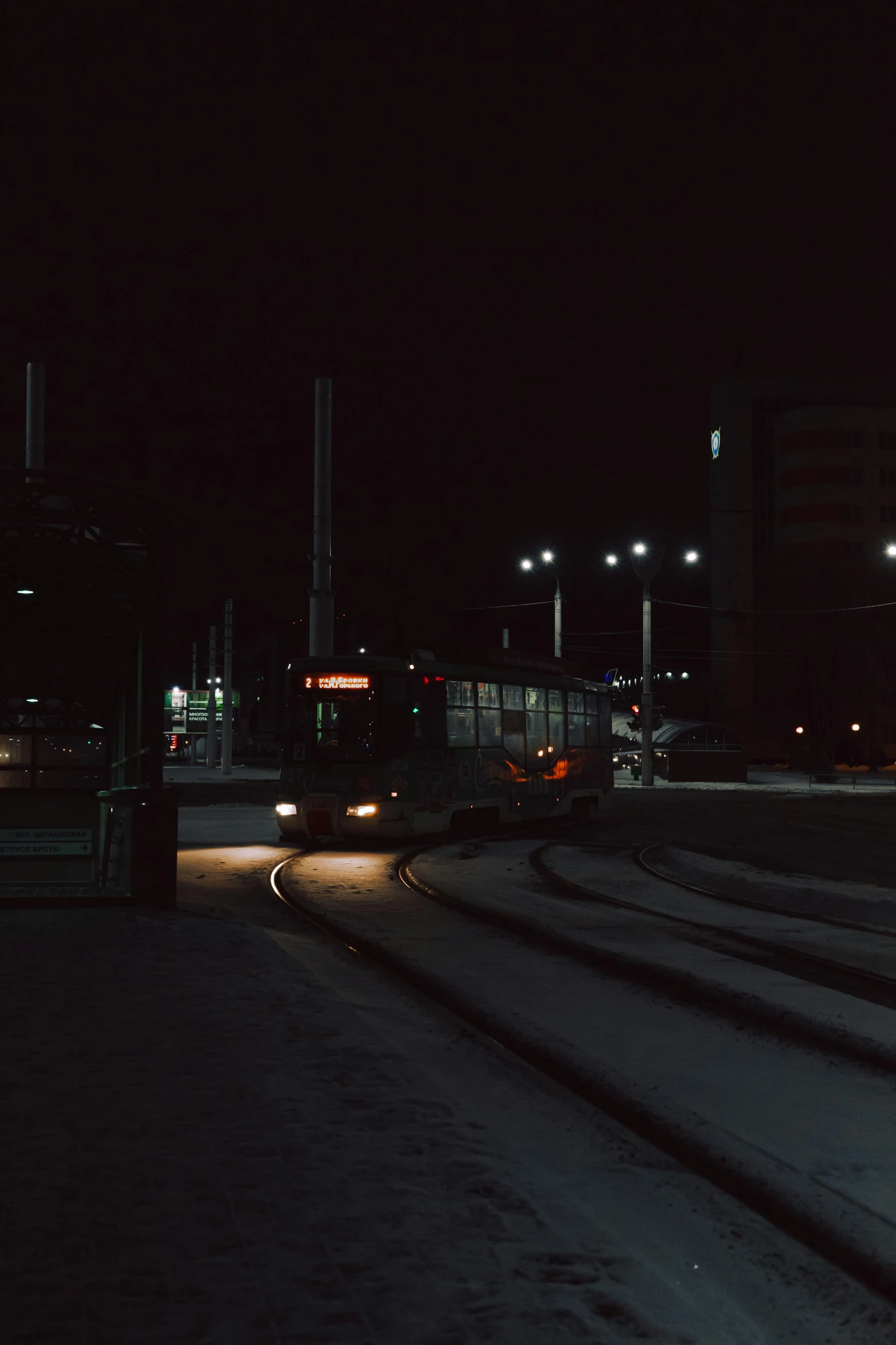 a train traveling down train tracks at night, a picture, by Brian Snøddy, unsplash, realism, bus station, low quality photo, cold winter, square