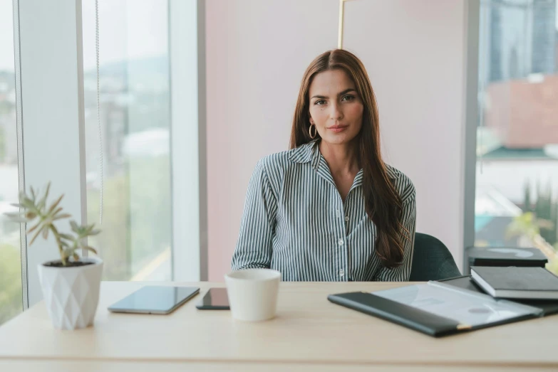 a woman sitting at a table with a cup of coffee, sat in an office, pokimane, genevieve o'reilly, avatar image