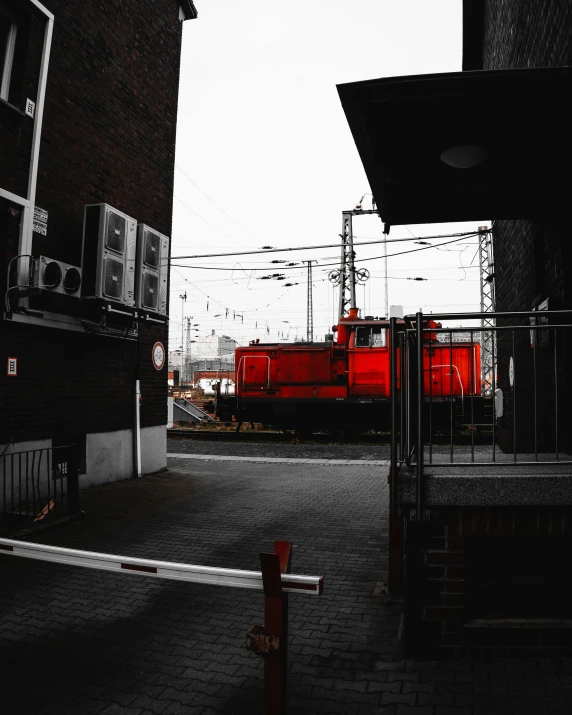 a red train traveling down train tracks next to a building, but as high contrast photography, instagram picture, gif, in front of a garage