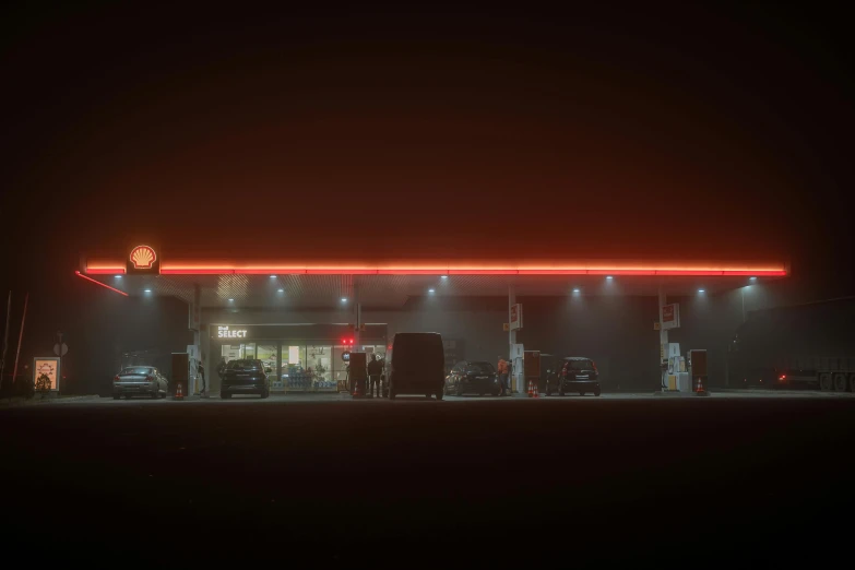 cars sit in front of a gas station at night