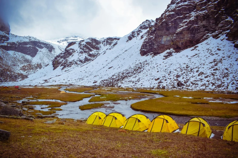 a group of tents sitting on top of a grass covered field, pexels contest winner, hurufiyya, snowy fjord, yellow theme, avatar image, assamese