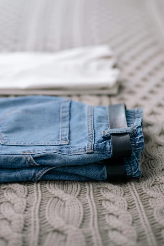 the folded jeans are sitting on top of the bed